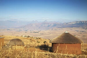 Village huts with Cathedral Peak in background, Ukhahlamba-Drakensberg Park, KwaZulu-Natal