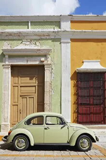 A vintage Volkswagen Bettle on a street of the historic center of Campeche with colorful houses in colonial