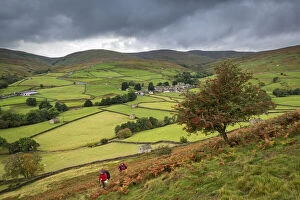 Two walkers walking on the Pennine Way through Swaledale in the Yorkshire Dales National Park, Thwaite, Yorkshire