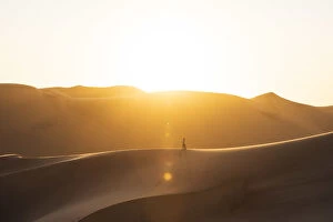 Walvis Bay, Namibia, Africa. Man walking on the sand dunes at sunset
