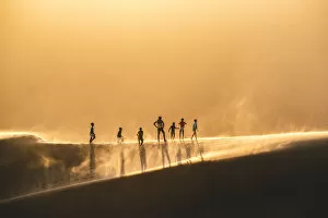 Walvis Bay, Namibia, Africa. People walking on the edge of a sand dune at sunset