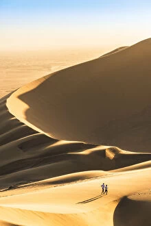 Walvis Bay, Namibia, Africa. Tourists walking on the sand dunes at sunset