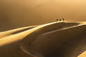 Walvis Bay, Namibia, Africa. Tourists walking on the sand dunes at sunset