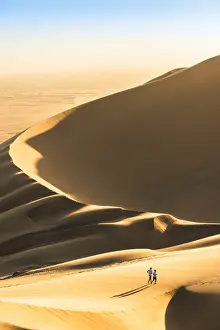 Walvis Bay, Namibia, Africa. Tourists walking on the sand dunes at sunset