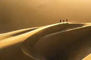 Walvis Bay, Namibia, Africa. Tourists walking on the sand dunes at sunset