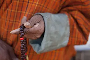 Hand Prints: Wangdue, Bhutan. A man in a Gho with a closeup of Bhuddist prayer beads