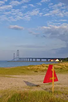 Warm Light Prints: Warm afternoon light illuminates a sandy beach leading towards the East Bridge, Korsor