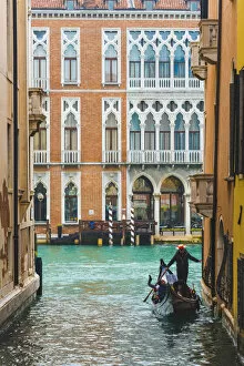 Waterfront palaces and tourists on gondola in a narrow canal tributary of the Grand Canal