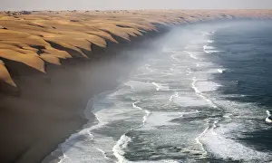 Dune Prints: The waves of the Atlantic Ocean crashing against the sandy wall of the Namib desert