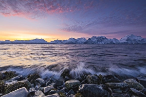 The waves breaking on the stones beach during sunset. Nordmannvik, Kafjord, Lyngen Alps