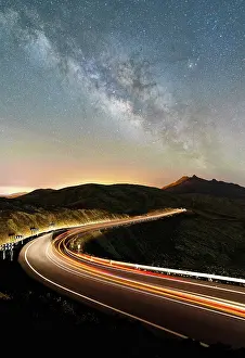 Speed Prints: Winding road with lights of car trails in the volcanic landscape under the Milky Way