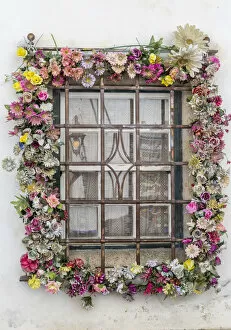 A window adorned with colorful flowers in the ancient fortified town of Obidos Oeste