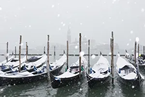 Winter snowfall in the city of Venice, gondolas covered by snow