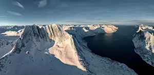 Q3 2023 Prints: Winter sunrise over Breidtinden mountain covered with snow overlooking the cold sea