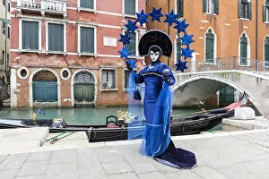Woman in blue costume posing by canal during Carnival, Venice, Veneto, Italy