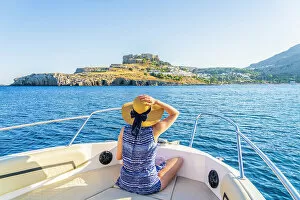 Acropolis Of Lindos Gallery: A woman on a boat looking at the Acropolis of Lindos, Lindos, Rhodes, Dodecanese Islands, Greece