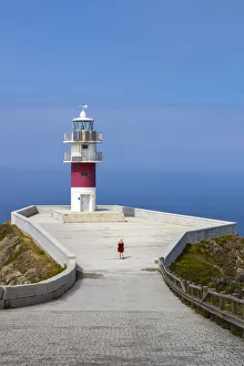 Galicia Prints: Woman at Cabo Ortegal and its lighthouse at sunrise, Galicia, Spain (MR)