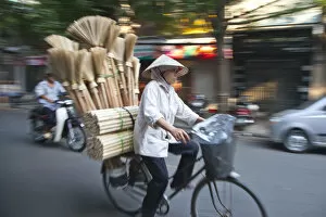 Woman carrying brooms on her bike, Old Quarter, Hanoi, Vietnam