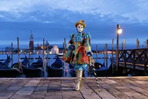 Mediterrranean Prints: A woman in a colourful costume stands in front of the lagoon during the Venice Carnival