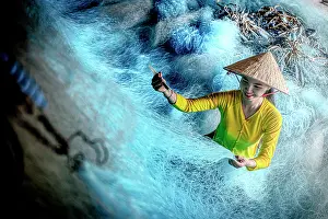 Smiling Prints: Woman with conical hat sewing a fishing net, Vietnam. (MR)