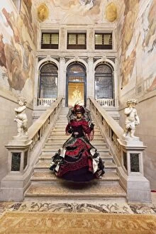 Woman in costume standing on staircase in Ca Segredo palace during Carnival, Venice