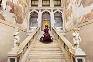 Woman in costume standing on staircase in Ca Segredo palace during Carnival, Venice