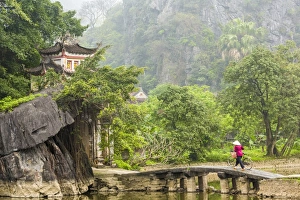 Bicycle Gallery: Woman crossing bridge with bicycle to temple, Tam Coc nr Ninh Binh, nr Hanoi, Vietnam