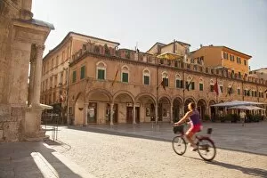Images Dated 4th August 2014: Woman cycling through Piazza del Popolo, Ascoli Piceno, Le Marche, Italy