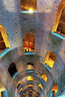 Spiral Prints: Woman descending the illuminated spiral staircase of Saint Patrick well