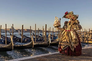 Images Dated 17th March 2020: A woman in an elaborate costume poses in front of the Venice lagoon during the Venice