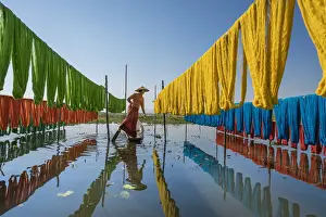 Woman hanging dyed yarn from a boat to dry in a traditional weaving village on Lake Inle
