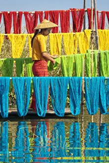 Woman hanging dyed yarn from a boat to dry in a traditional weaving village on Lake Inle