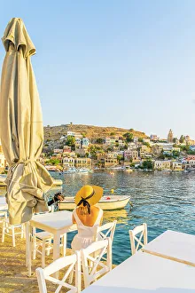 Images Dated 10th January 2023: A woman in a hat by the colourful harbour in Symi, Dodecanese Islands, Greece. (MR)