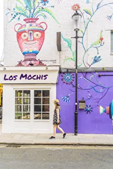 A woman in a hat walking, past a street mural in Notting Hill, London, England, Uk, (MR) A woman in a hat walking, past a street mural in Notting Hill, London, England, Uk, (MR)