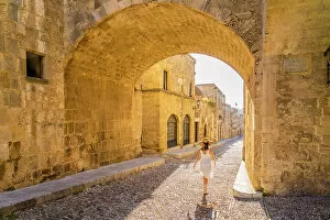 Images Dated 10th January 2023: A woman in a hat walking in the Street of the Knights of Rhodes, in the Medieval City of Rhodes