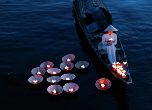 Candle Prints: Woman laying floating lanterns on the Perfume River at dusk, Hue, Central Vietnam