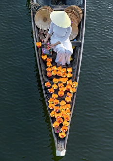 Candle Prints: Woman laying floating lanterns on the Perfume River at dusk, Hue, Central Vietnam