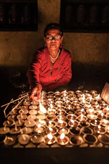 Images Dated 14th September 2023: Woman lighting devotional candles in temple at Swayambhunath Stupa, Kathmandu, Nepal