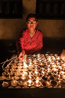 Himalaya Prints: Woman lighting devotional candles in temple at Swayambhunath Stupa, Kathmandu, Nepal