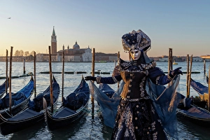 Mediterrranean Prints: A woman poses in costume in front of the lagoon during the Venice Carnival, Venice, Italy