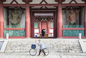 Images Dated 21st October 2014: Woman pushing bicycle past Shitenno-ji temple, Tennoji, Osaka, Kansai, Japan