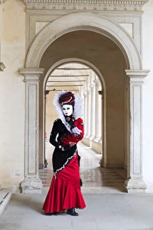Images Dated 9th February 2018: A woman in a red costume and mask poses in an archway during the Venice Carnival