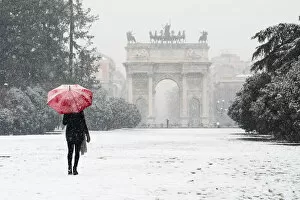 Tourist Collection: A woman with red umbrella walks in Sempione park during a snowfall. Milan, Lombardy