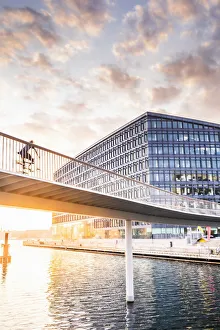 A woman riding a bike on the bike bridge over the water canal
