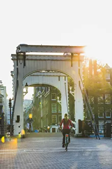 Bicycle Gallery: A woman riding a bike on a bridge over Amsterdam Canal, Holland / Netherlands
