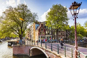 Bicylces Gallery: A woman riding a bike on a bridge over a canal in Amsterdam, Holland / Netherlands