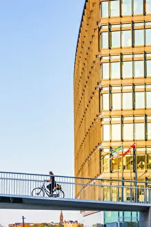 Bicylces Gallery: A woman riding a bike on a suspended bridge in Copenhagen at sunset, Denmark