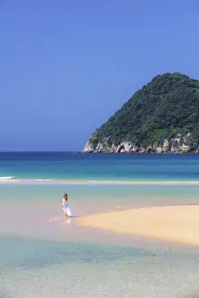 A woman walking on the beach at Awaroa Inlet along the Abel Tasman national park