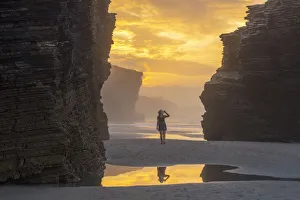 Galicia Prints: Woman walks at Playa de Las Catedrales at sunset