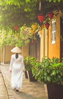Wearing Prints: Woman wearing Ao Dai dress walking along street, Hoi An (UNESCO World Heritage Site)
